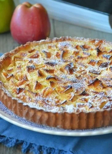 Tarte Normande aux pommes fraîchement cuite, présentée sur une table.
