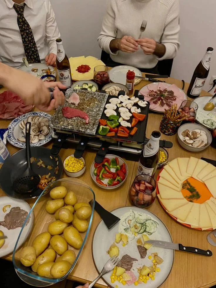 Raclette fondue avec pommes de terre et légumes grillés sur une table conviviale.